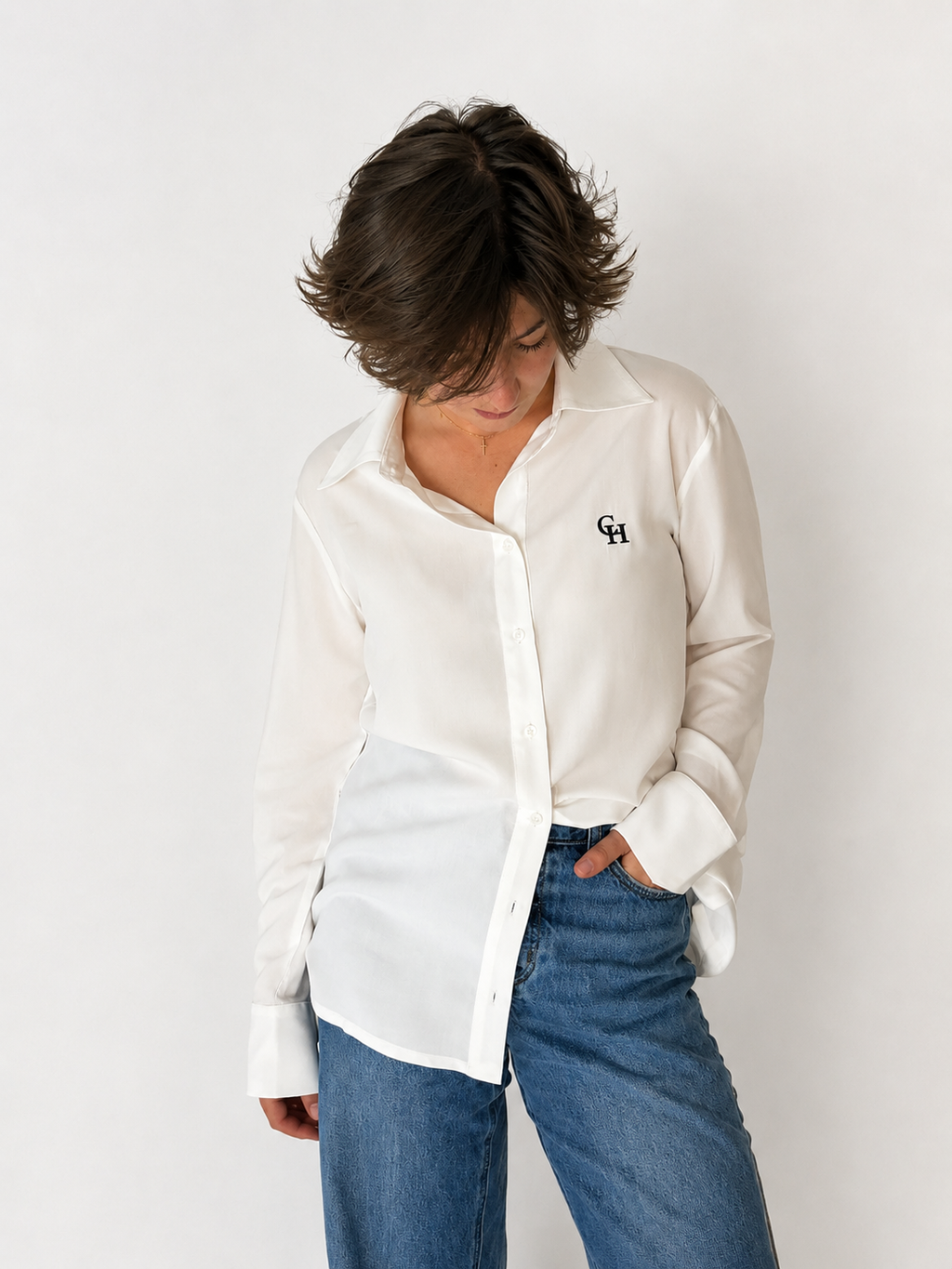 Model wearing the Essence Shirt in white, styled with blue jeans. The image highlights the relaxed fit, classic collar, embroidered Courthill XIX monogram, and clean, timeless silhouette.