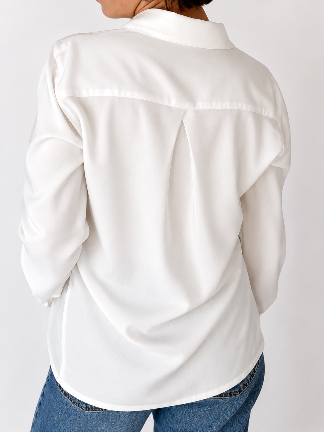 Back view of the Essence Shirt in white, showcasing the relaxed oversized fit, clean back yoke with center pleat, soft drape, and minimalist tailoring for effortless everyday elegance.