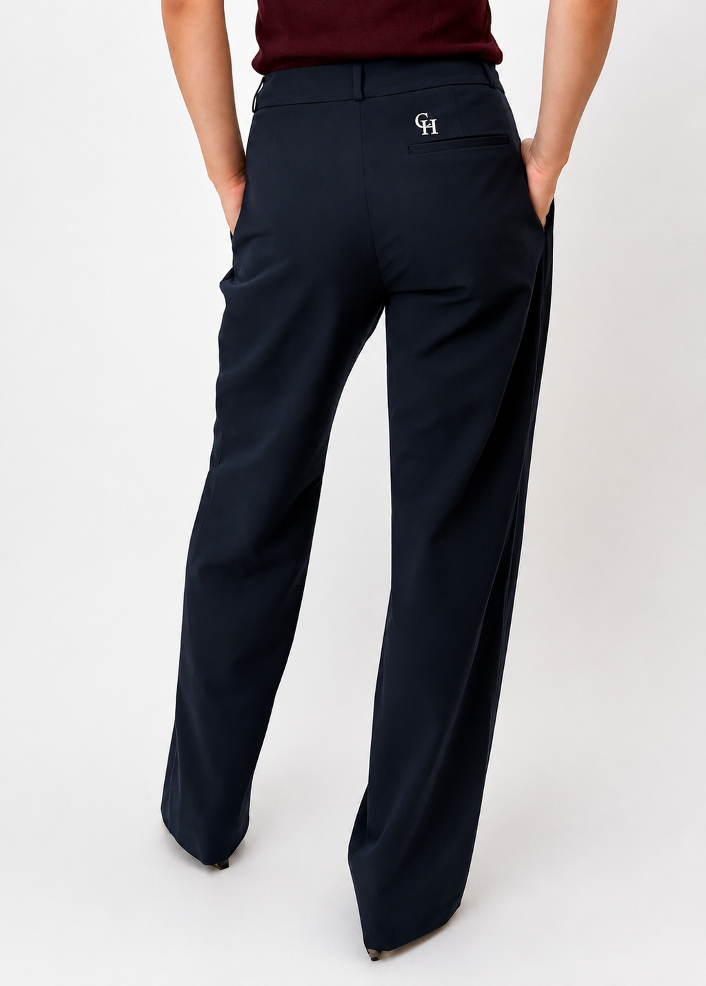 Back view of the Founder's Cut trousers in navy, highlighting the clean tailored fit, wide-leg silhouette, welt back pocket with embroidered Courthill XIX monogram, and elegant minimalist finish. Styled with a burgundy knit top.